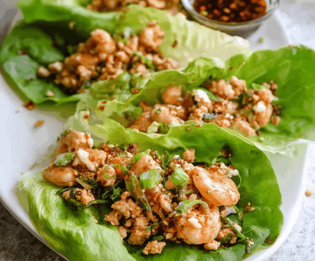 Fresh chicken and shrimp lettuce wraps with colorful vegetables and flavorful herbs, perfect for a healthy appetizer or light meal.