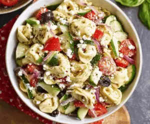 Delicious Greek tortellini pasta salad with fresh vegetables and feta cheese served in a bowl.